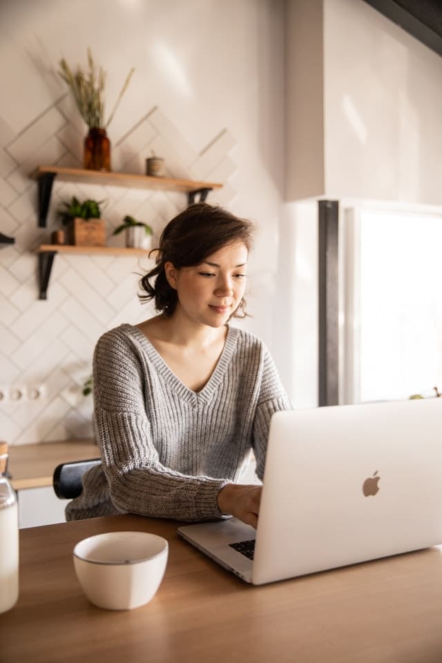 Woman working on her Apple computer in her kitchen